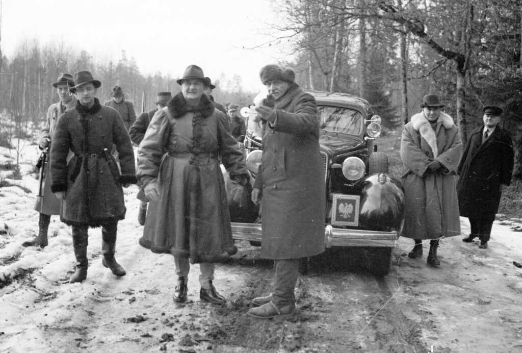 Regent Węgier Miklos Horthy słucha objaśnień prezydenta RP Ignacego Mościckiego (w futrzanej czapce) przed polowaniem. Towarzyszy im marszałek Edward Rydz-Śmigły (2. z prawej). Widoczny także adiutant prezydenta RP kpt. Stefan Kryński (na lewo za regentem Horthym).